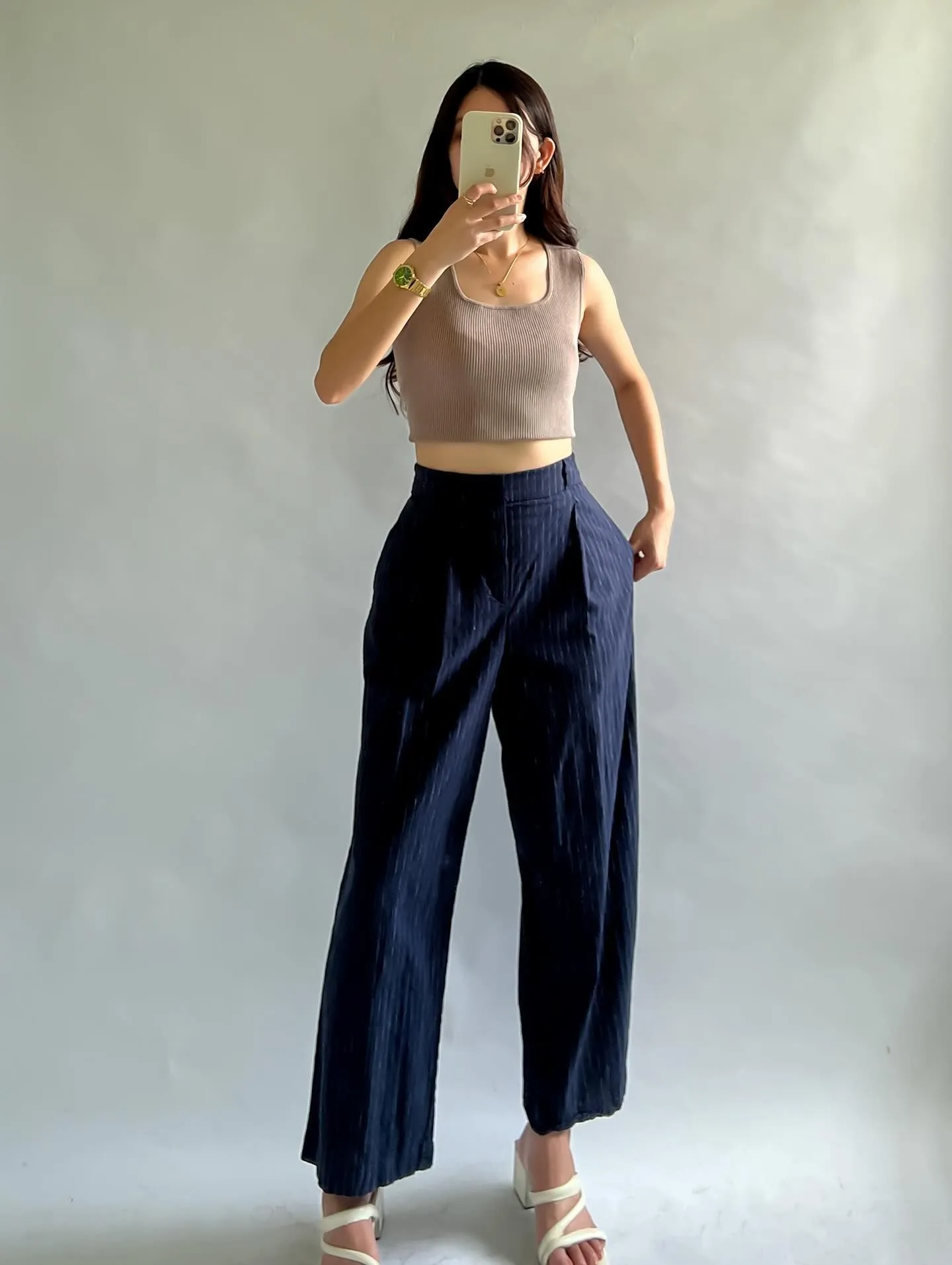 Curvy model wearing navy blue pleated wide-leg trousers and a silk camisole