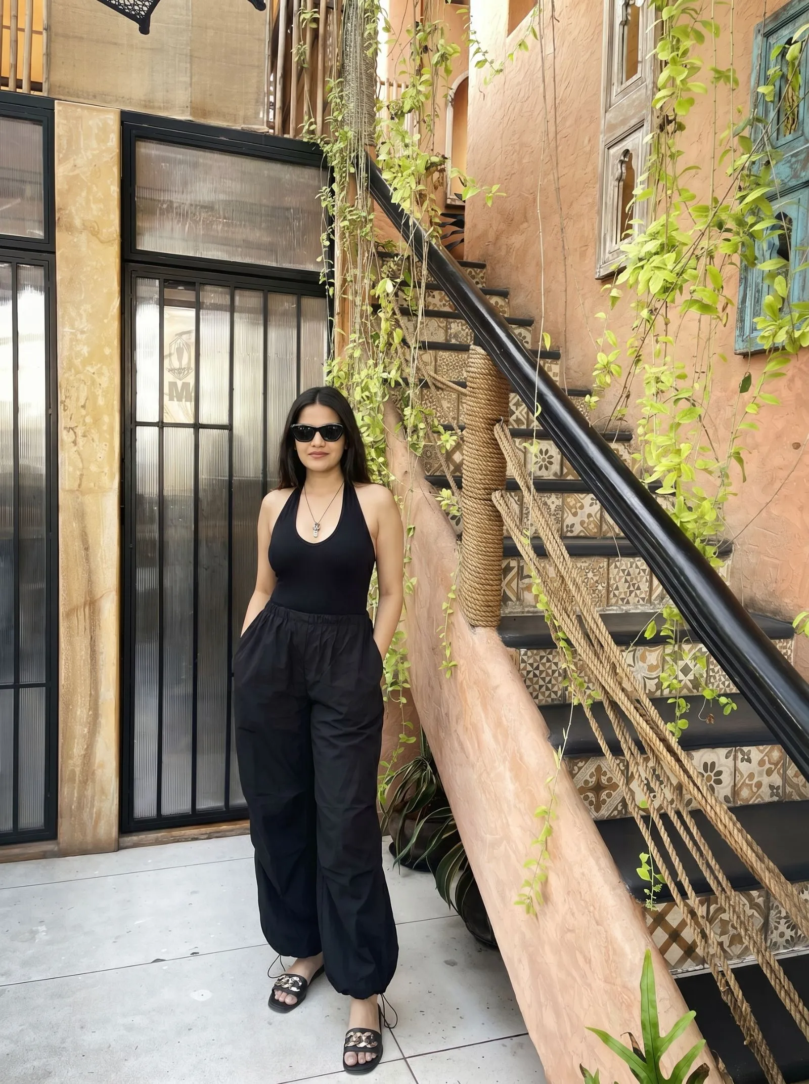 Woman wearing wide-leg parachute pants and a halter bodysuit on a sunny city street