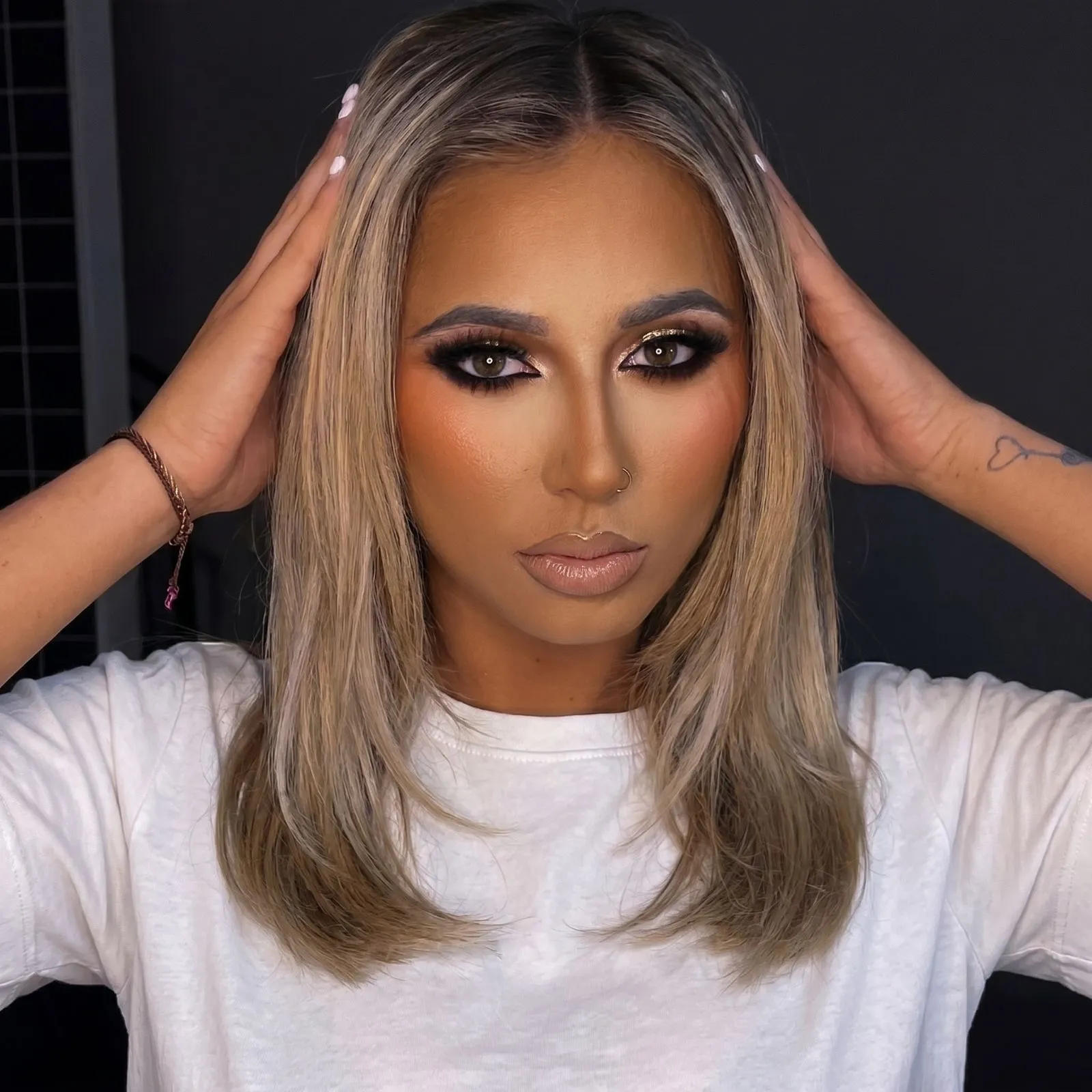 Woman with deep glowing skin wearing apricot cream blush and a white cotton shirt