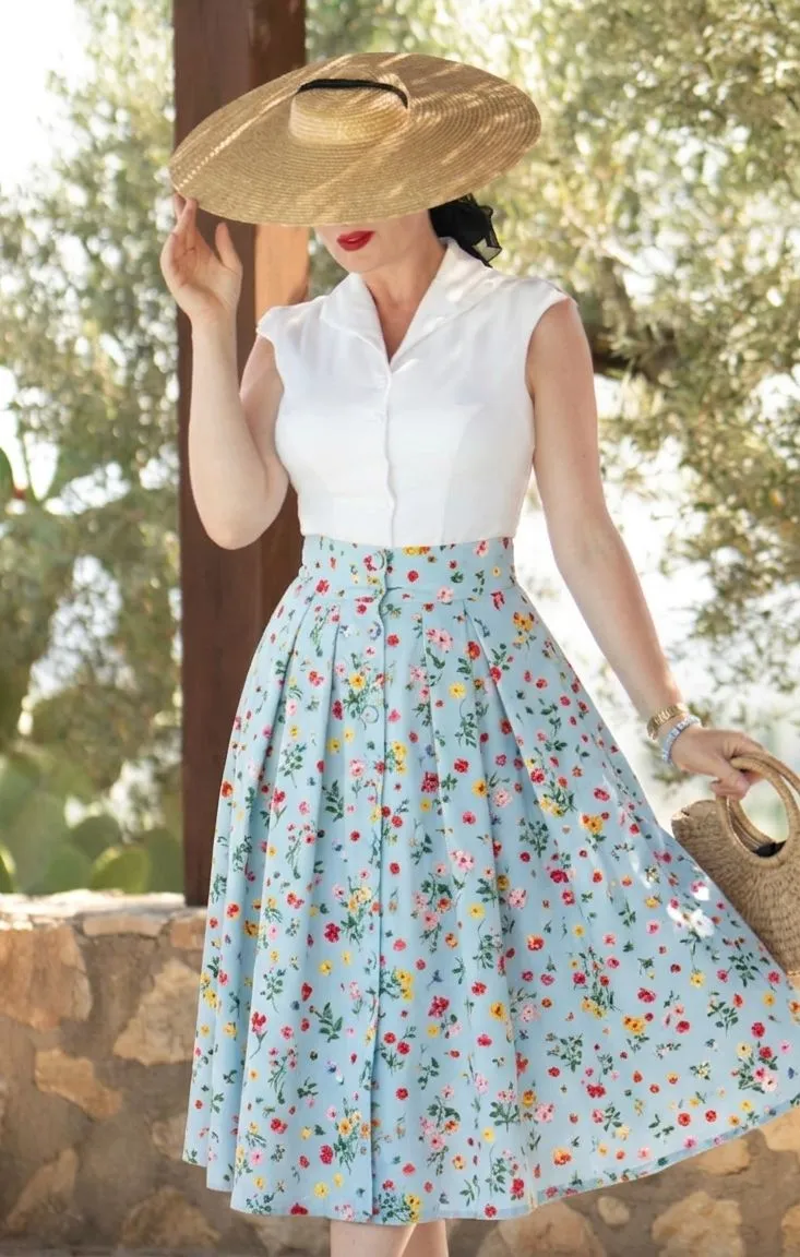 Woman in a floral midi skirt and straw hat for a summer concert
