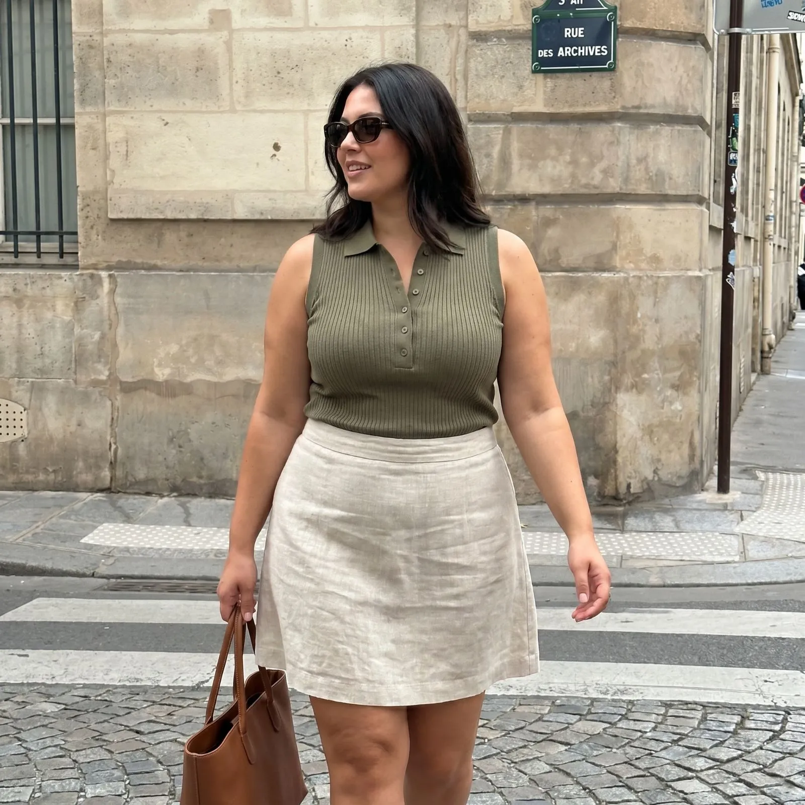 Curvy woman wearing an olive green sleeveless polo with a linen skirt