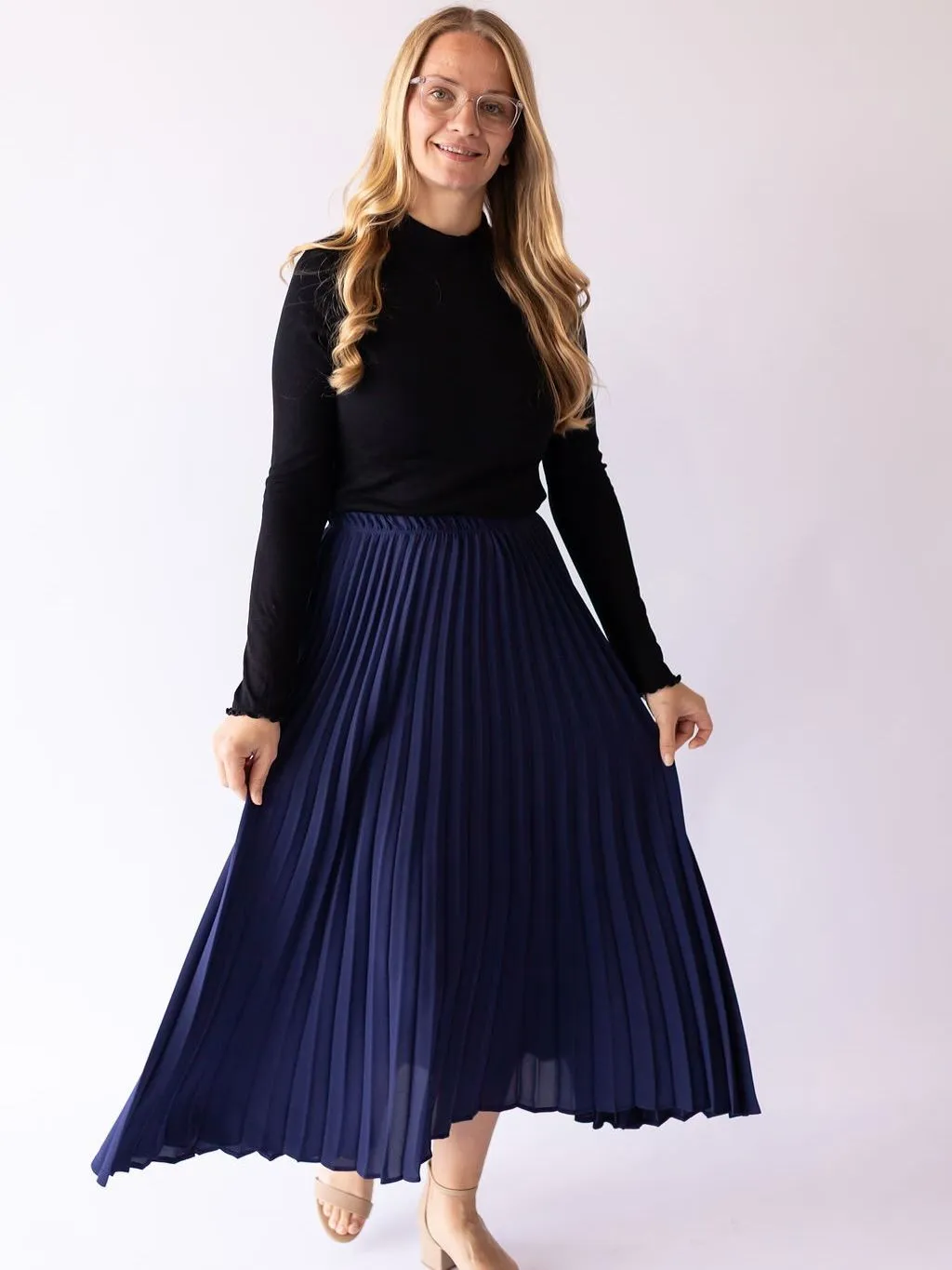 Plus size model wearing a flattering navy pleated skirt and cream knit top