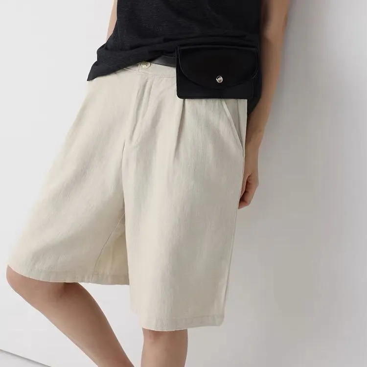 Woman styling tailored olive green linen shorts with a satin blouse