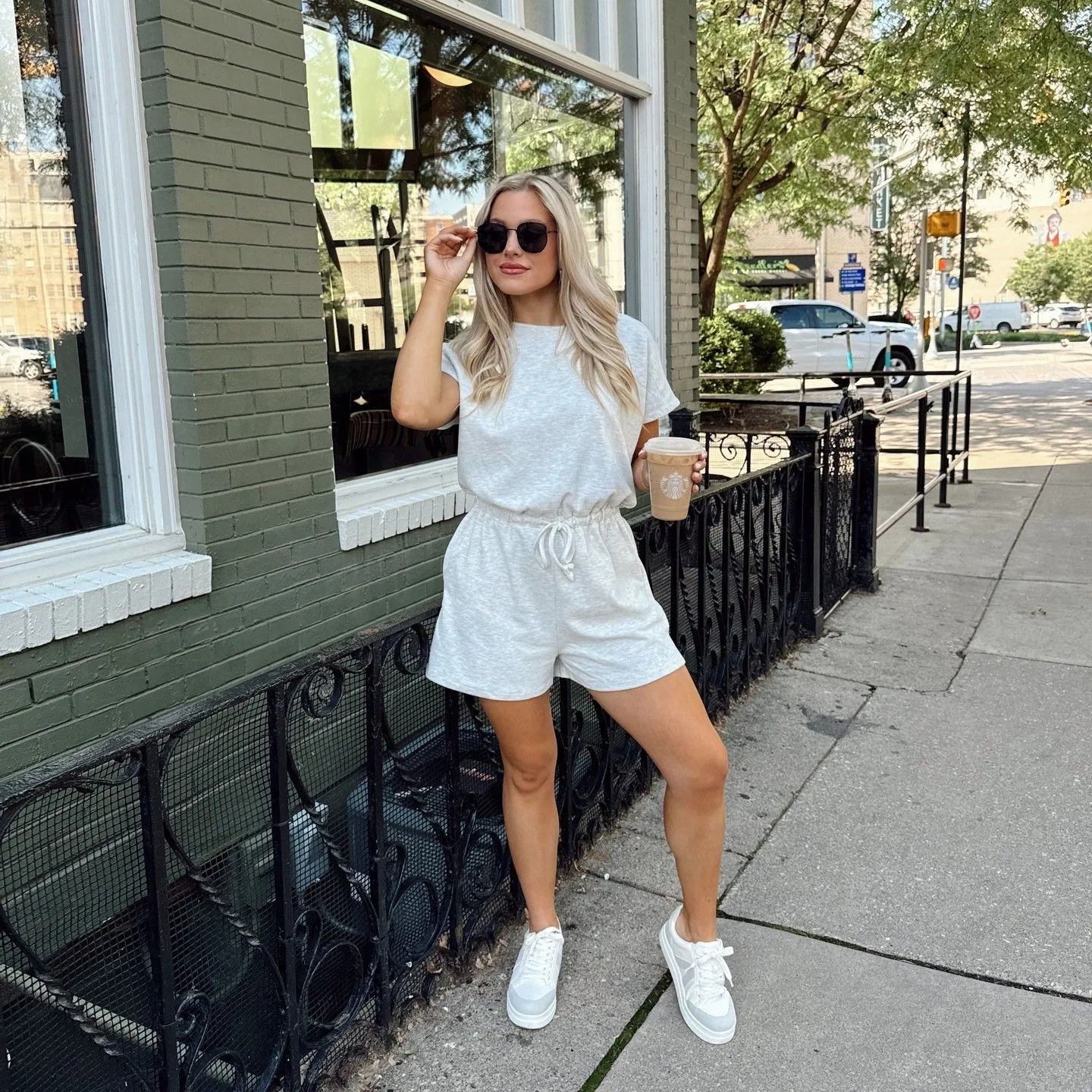 Woman wearing a breathable white cotton romper with edgy black accessories on a sunny street