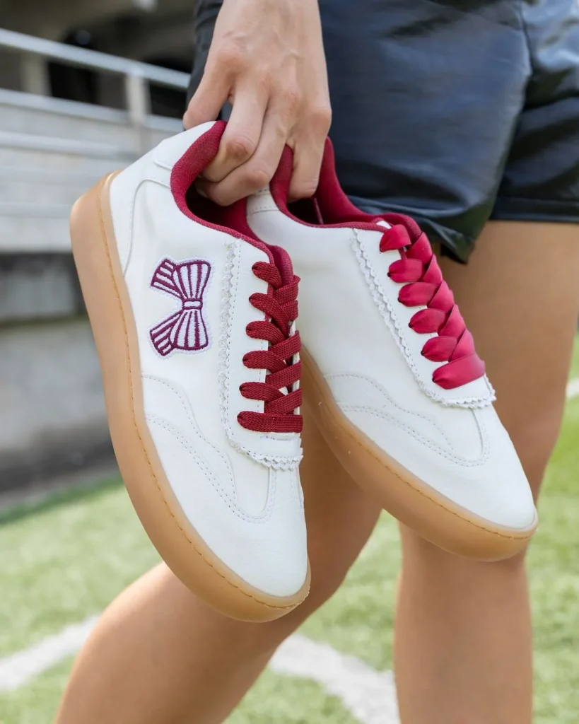 White leather sneakers paired with a denim skirt at a baseball stadium