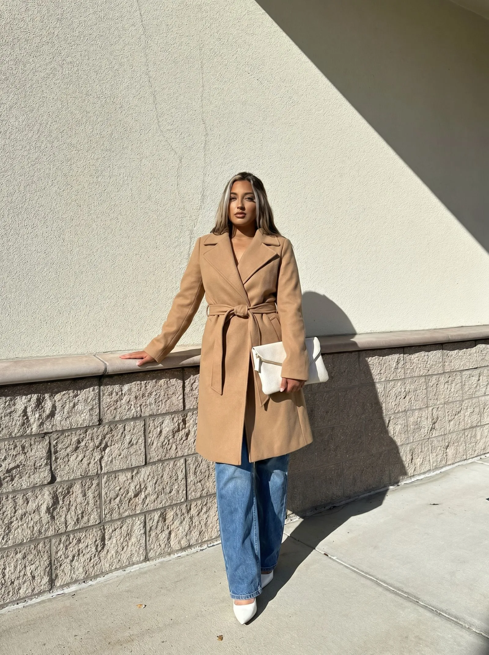 Curvy woman wearing a camel belted wrap coat and straight-leg jeans for fall