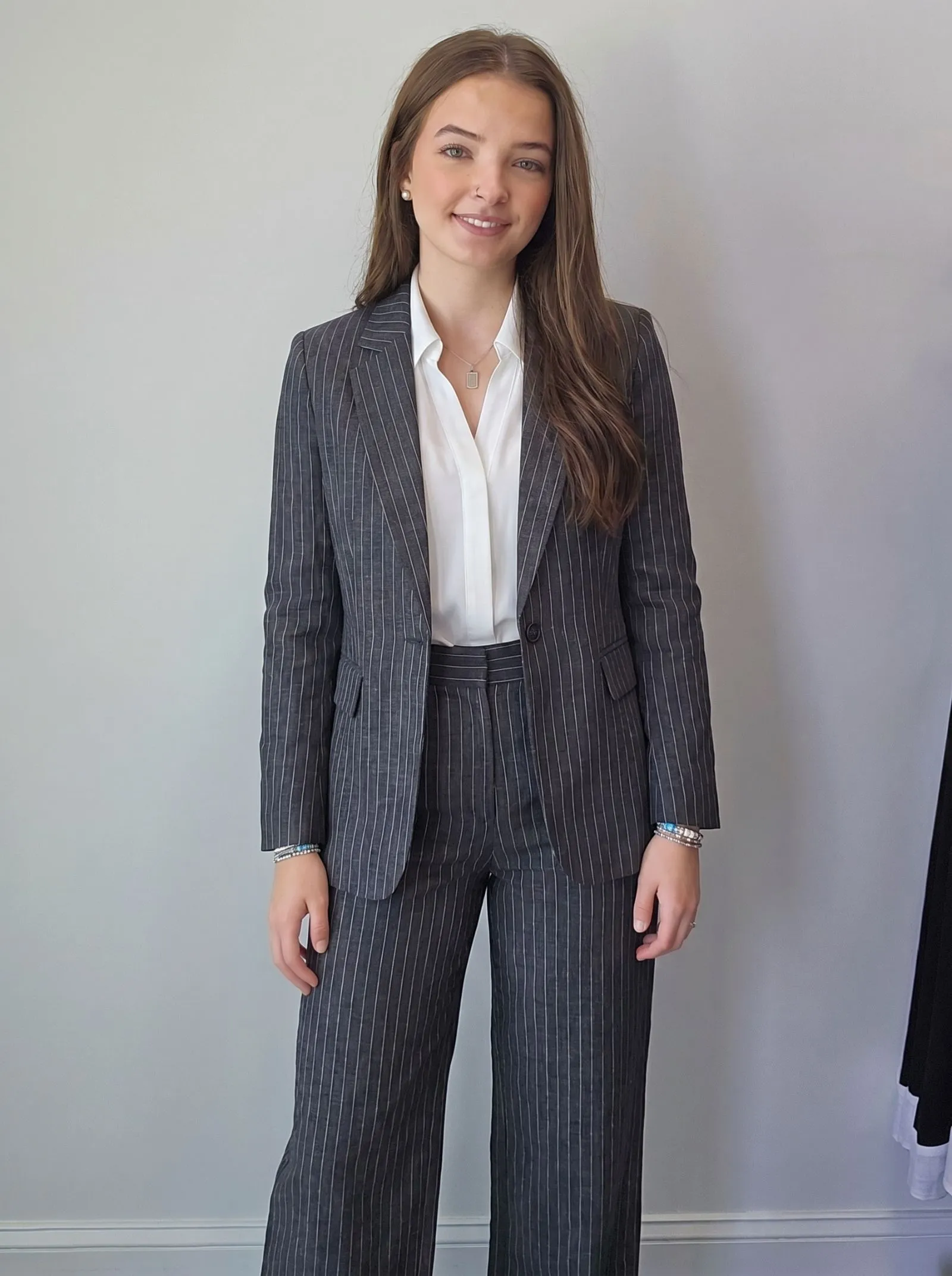 Female CEO wearing a tailored charcoal pinstripe linen pantsuit for evening networking