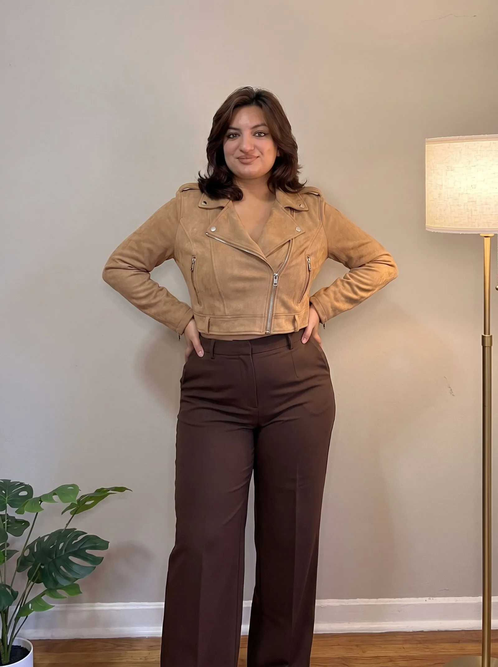 Curvy woman wearing a cropped suede biker jacket and wide leg pants
