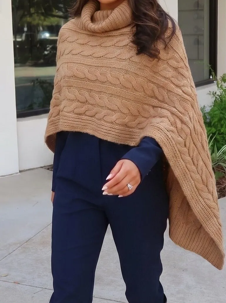 Close up of a chunky camel knit poncho layered over a dark jumpsuit