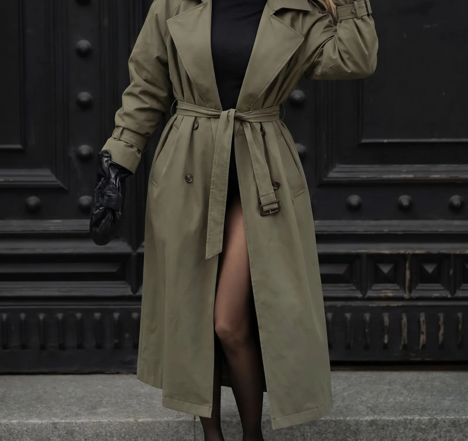 Close up of a belted olive trench coat over a black ribbed turtleneck