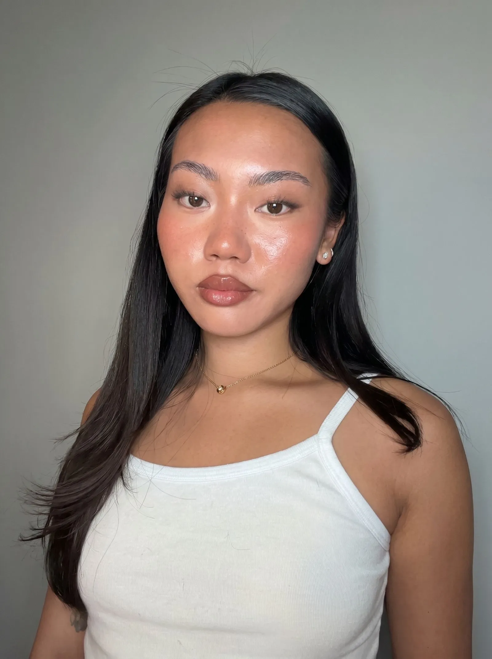 Woman with dark skin wearing dewy highlighter and crimson matte lipstick