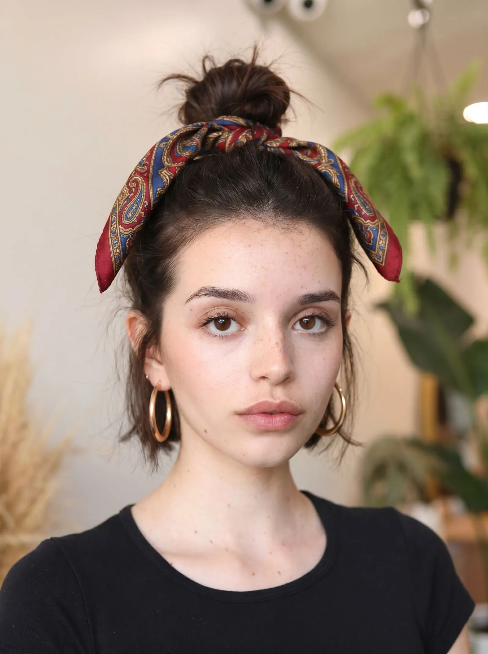Woman with short brunette hair wearing a silk bandana in a top knot