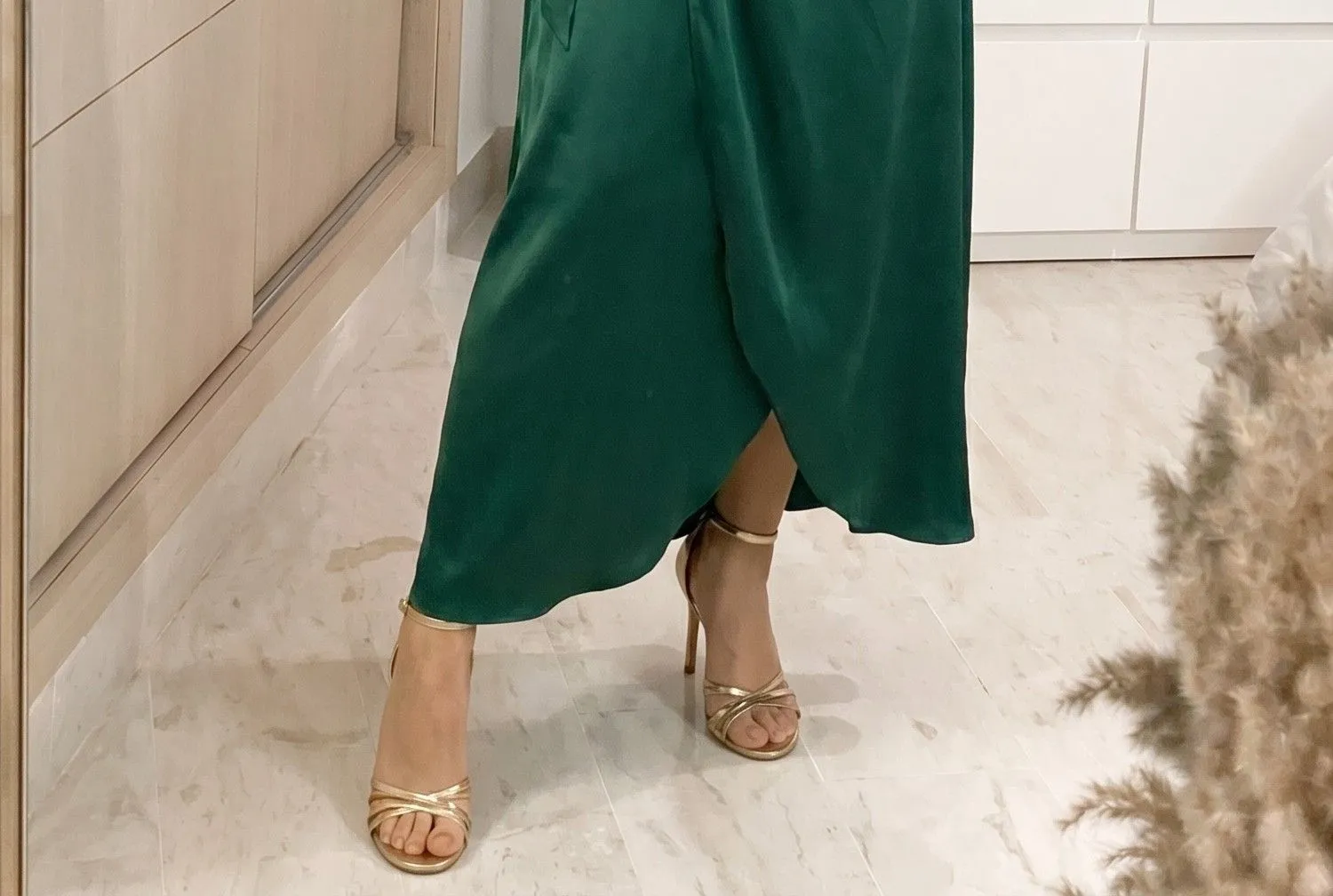 Close up of gold strappy heels paired with a flowing satin wrap dress