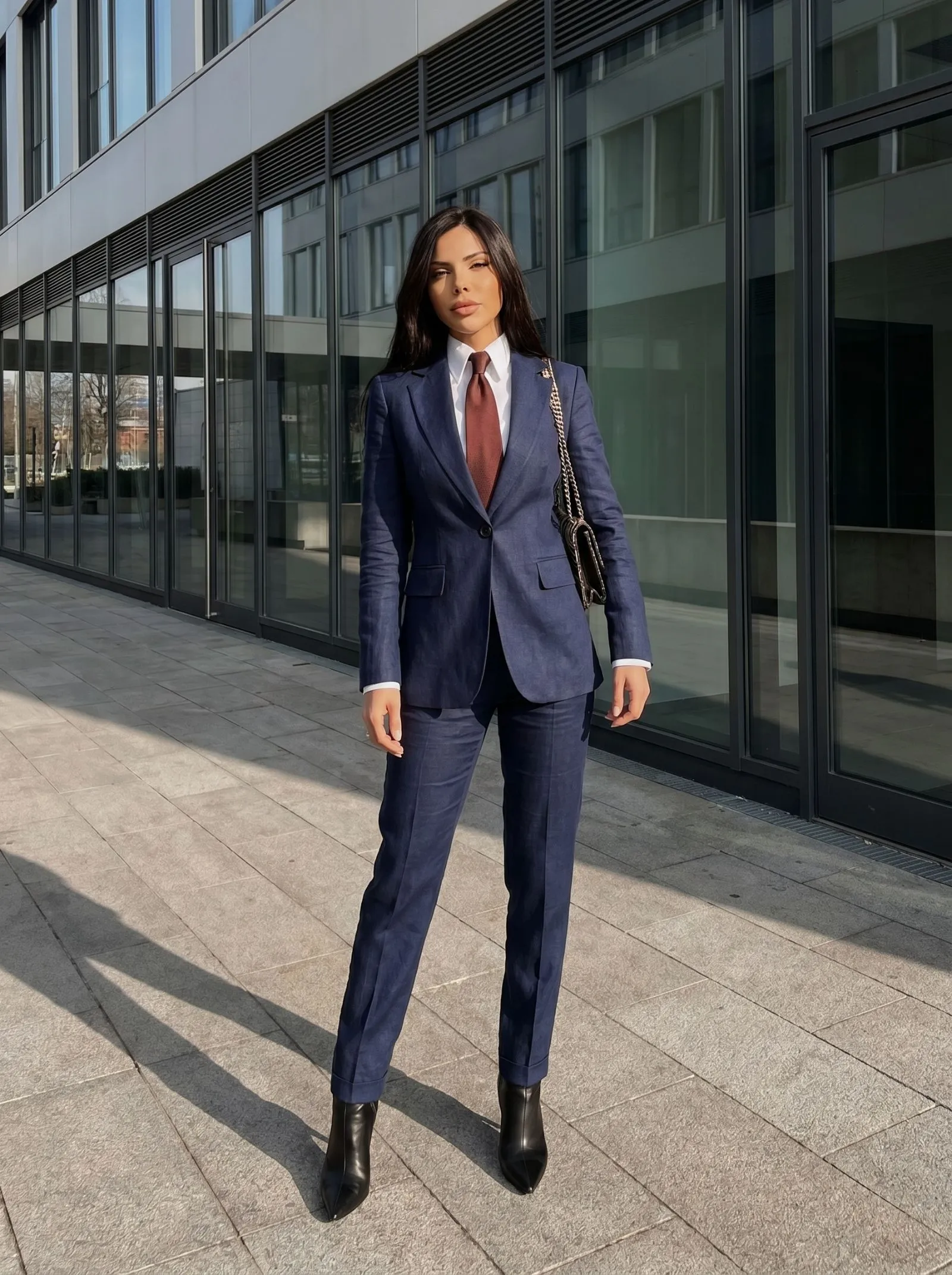Female CEO wearing a structured navy linen pantsuit in a modern boardroom