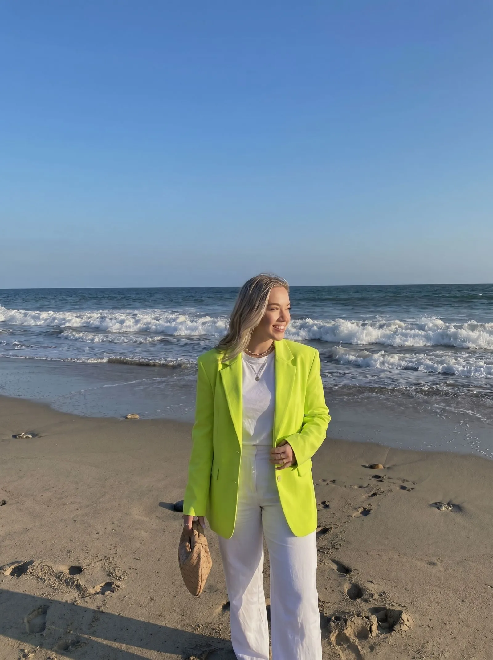Woman wearing a neon lime power-shoulder blazer on a cruise deck at sunset