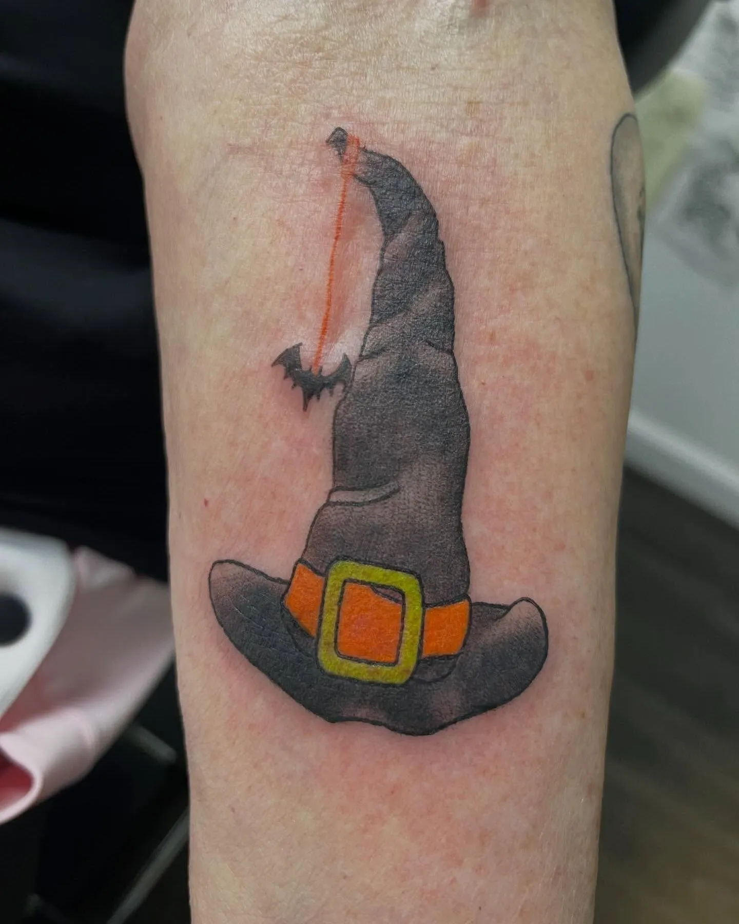 Close up of a cute pastel sparkly witch hat tattoo on bronze skin