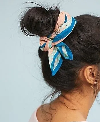 Hands tying a silk bandana around a hair bun