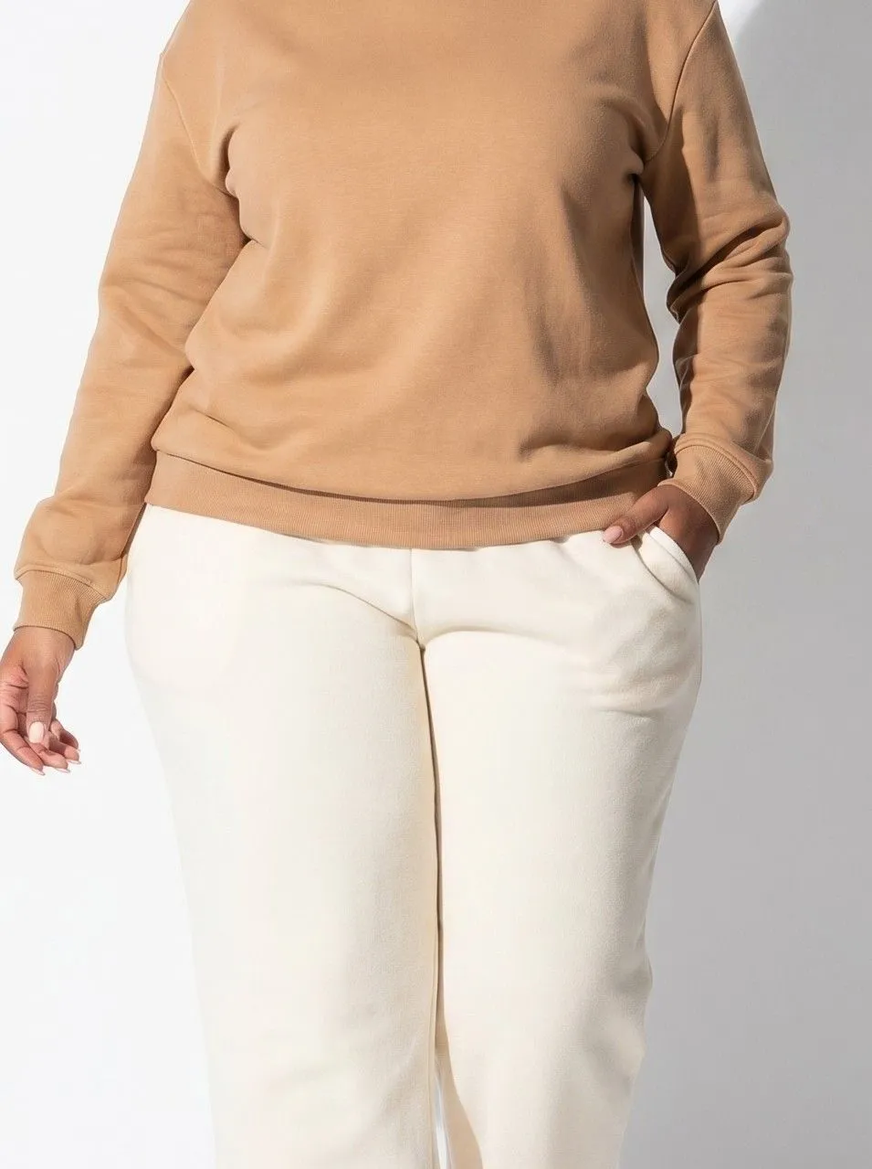Close up detail of a tailored crewneck sweater tucked into wide leg fleece joggers