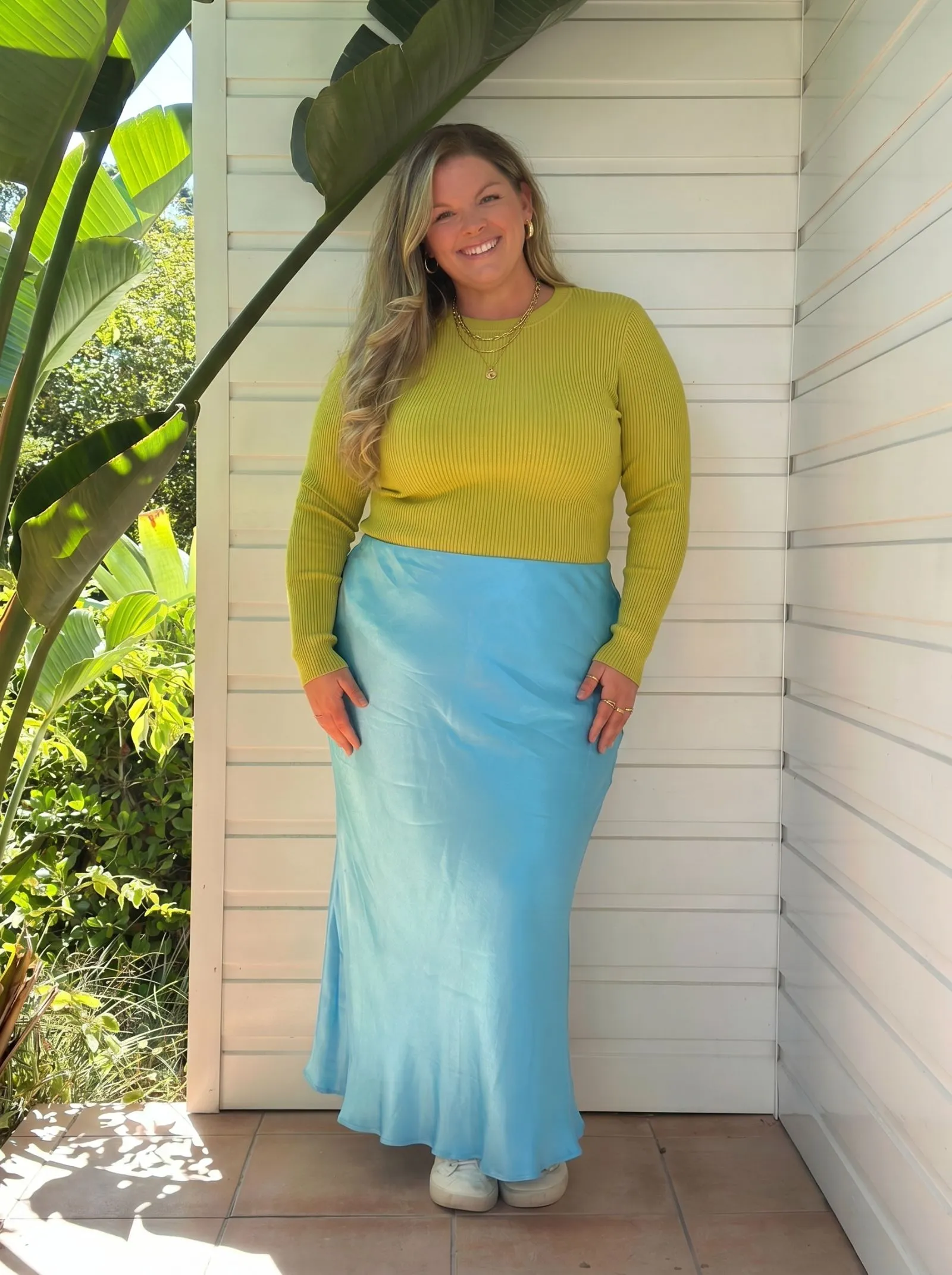 Plus size model styling a chartreuse ribbed knit top with gold jewelry