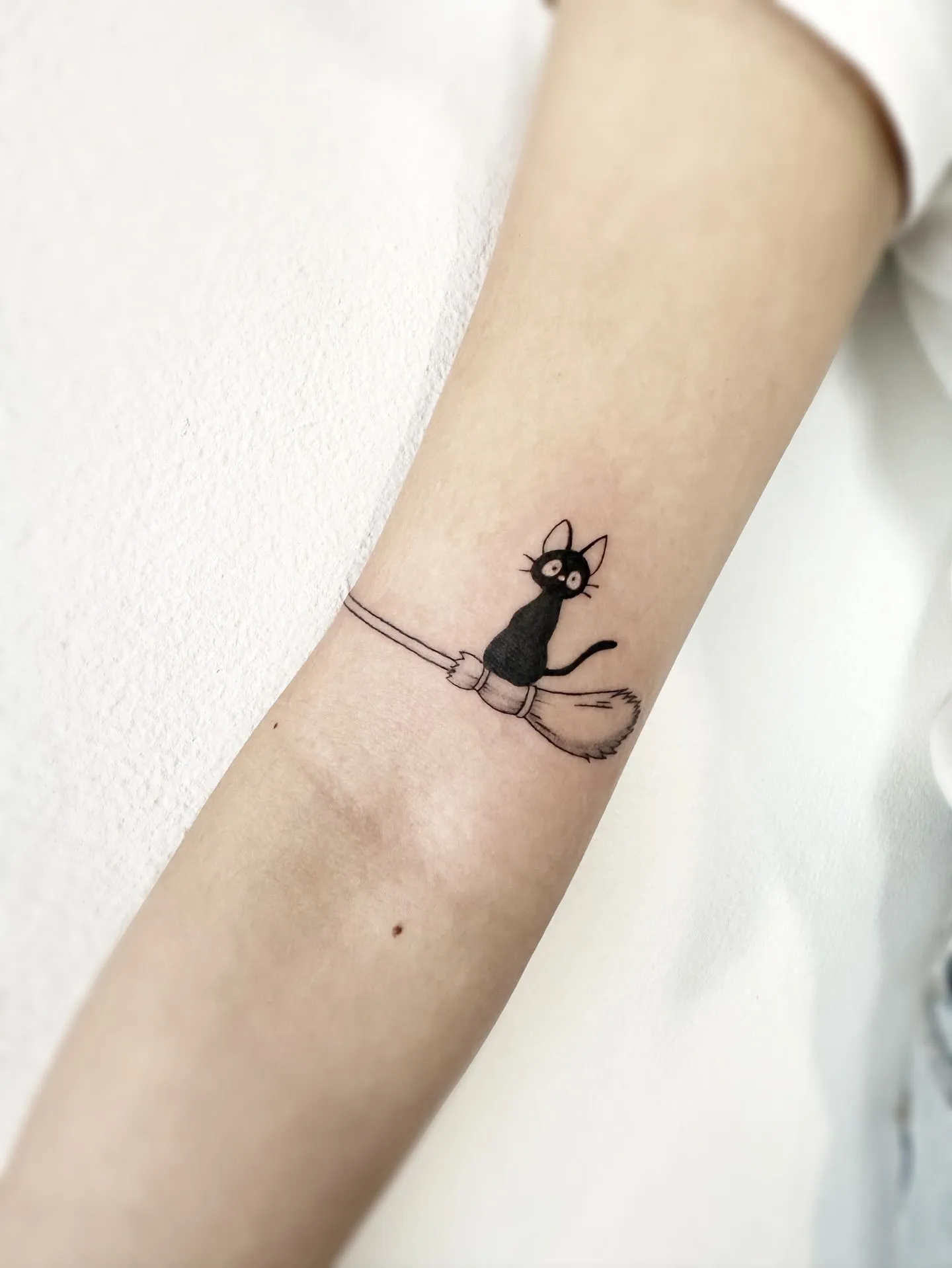 Small black cat silhouette tattoo on a wrist