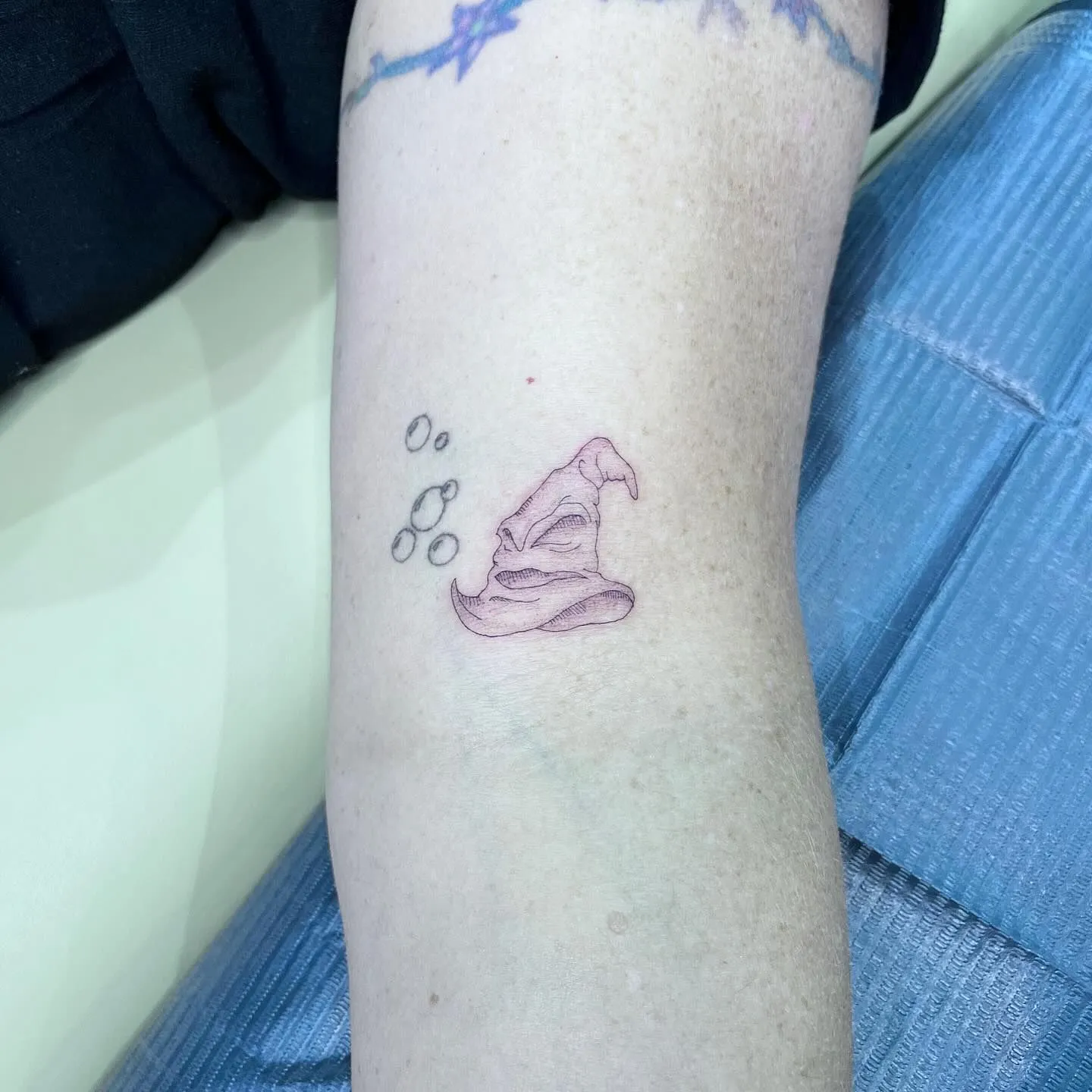 Small pastel witch hat tattoo on a person